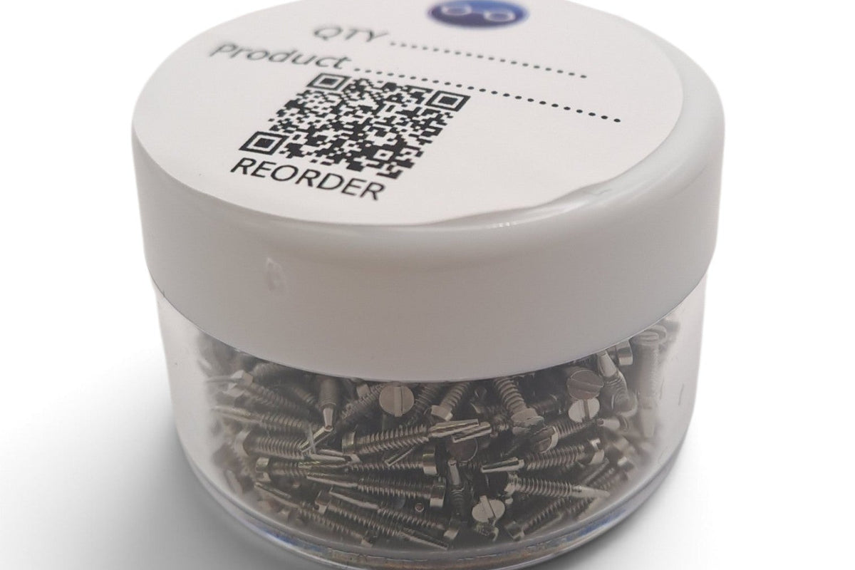 A small clear plastic jar filled with many small metallic screws with a white screw-on lid. The lid has printed text and a QR code, including the words 'QTY', 'Product', and 'REORDER'.